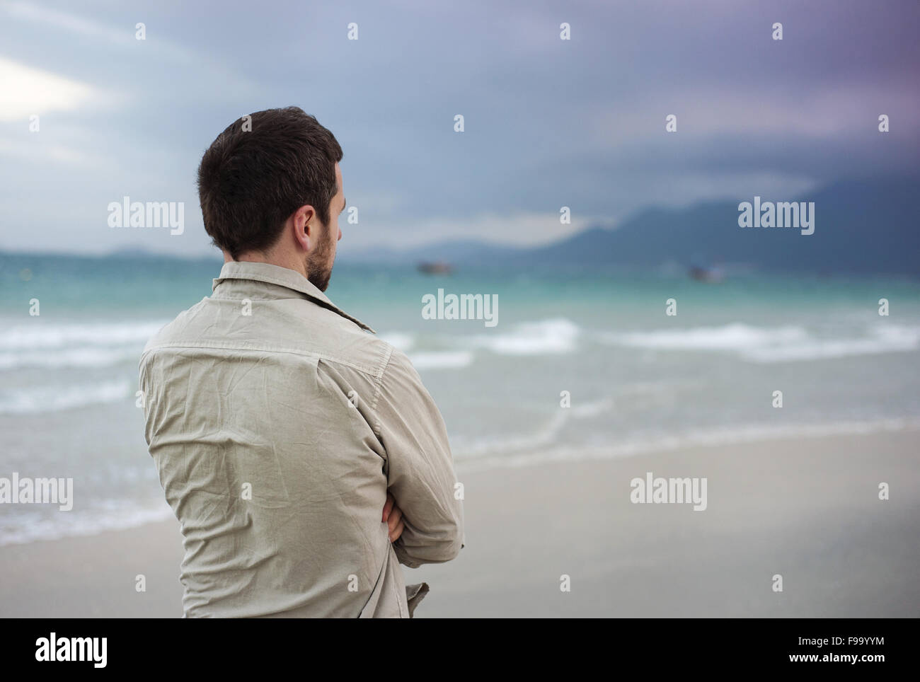 Bel giovane uomo caucasico camminare da solo sulla spiaggia Foto Stock