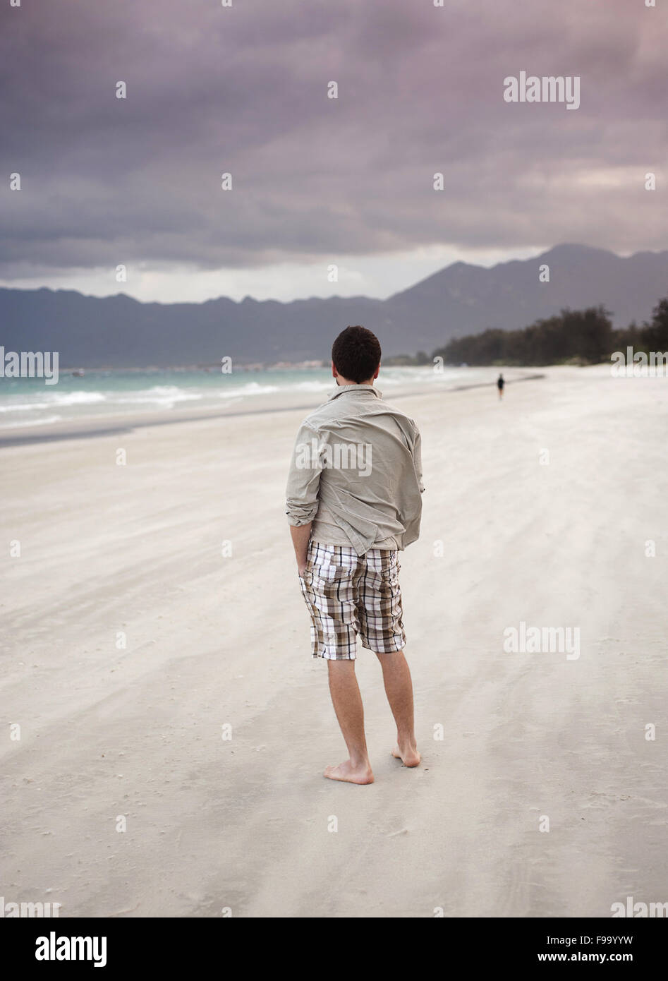 Bel giovane uomo caucasico camminare da solo sulla spiaggia Foto Stock