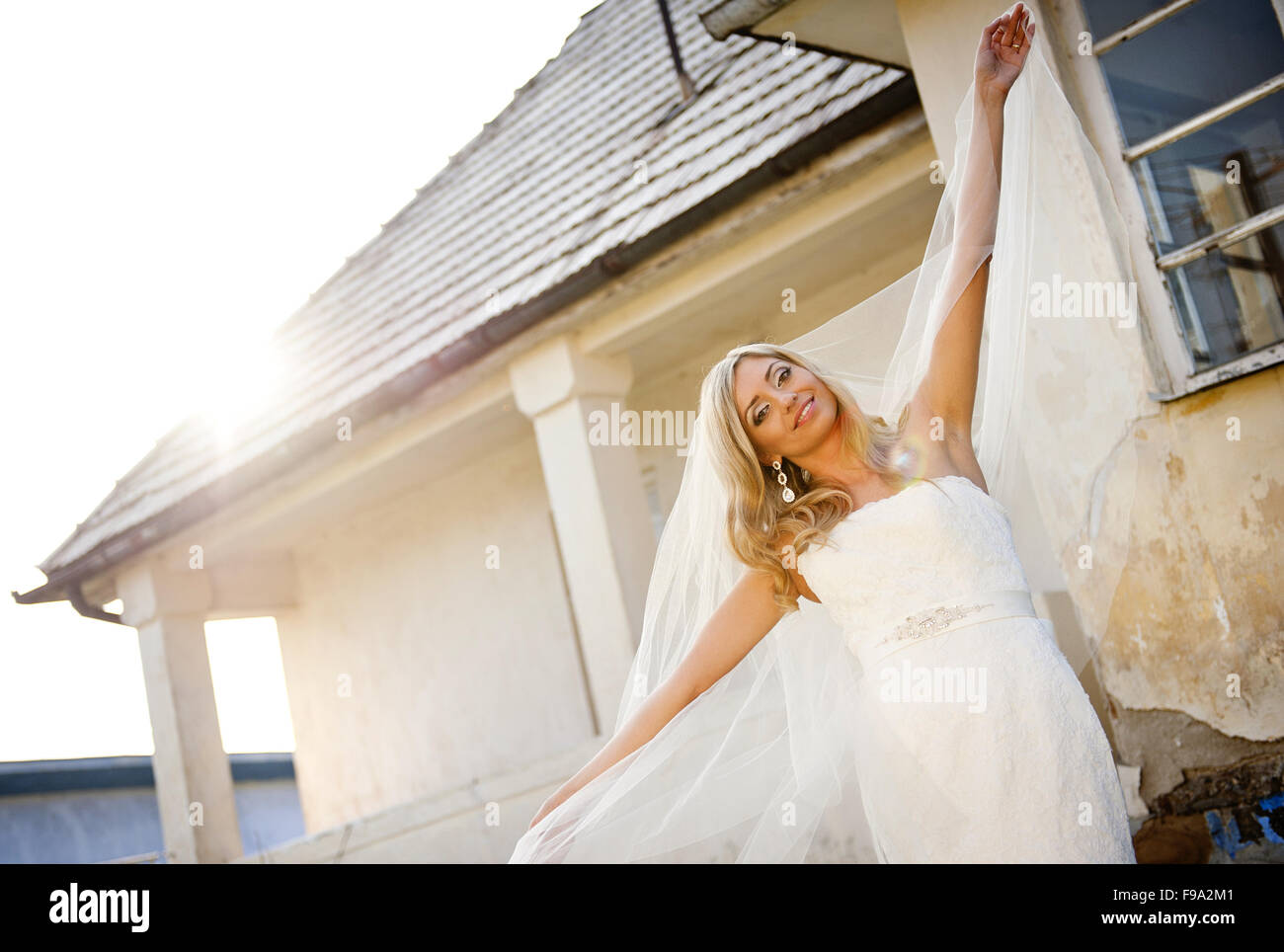 Bella bionda e giovane sposa con velo in posa da casa vecchia Foto Stock
