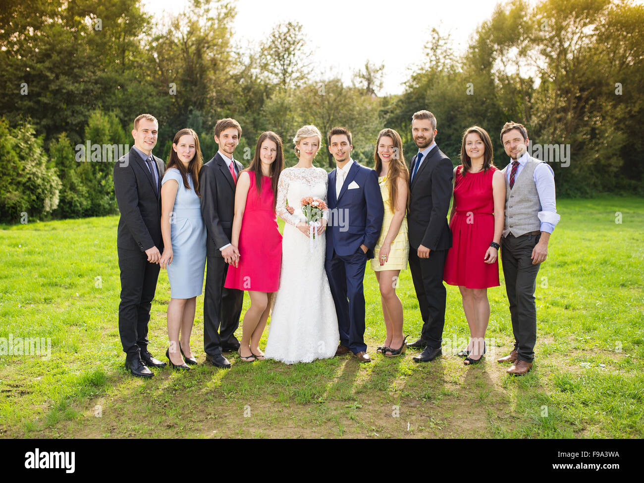 A piena lunghezza Ritratto di sposa giovane in posa con damigelle e groomsmen nel verde parco di sole Foto Stock