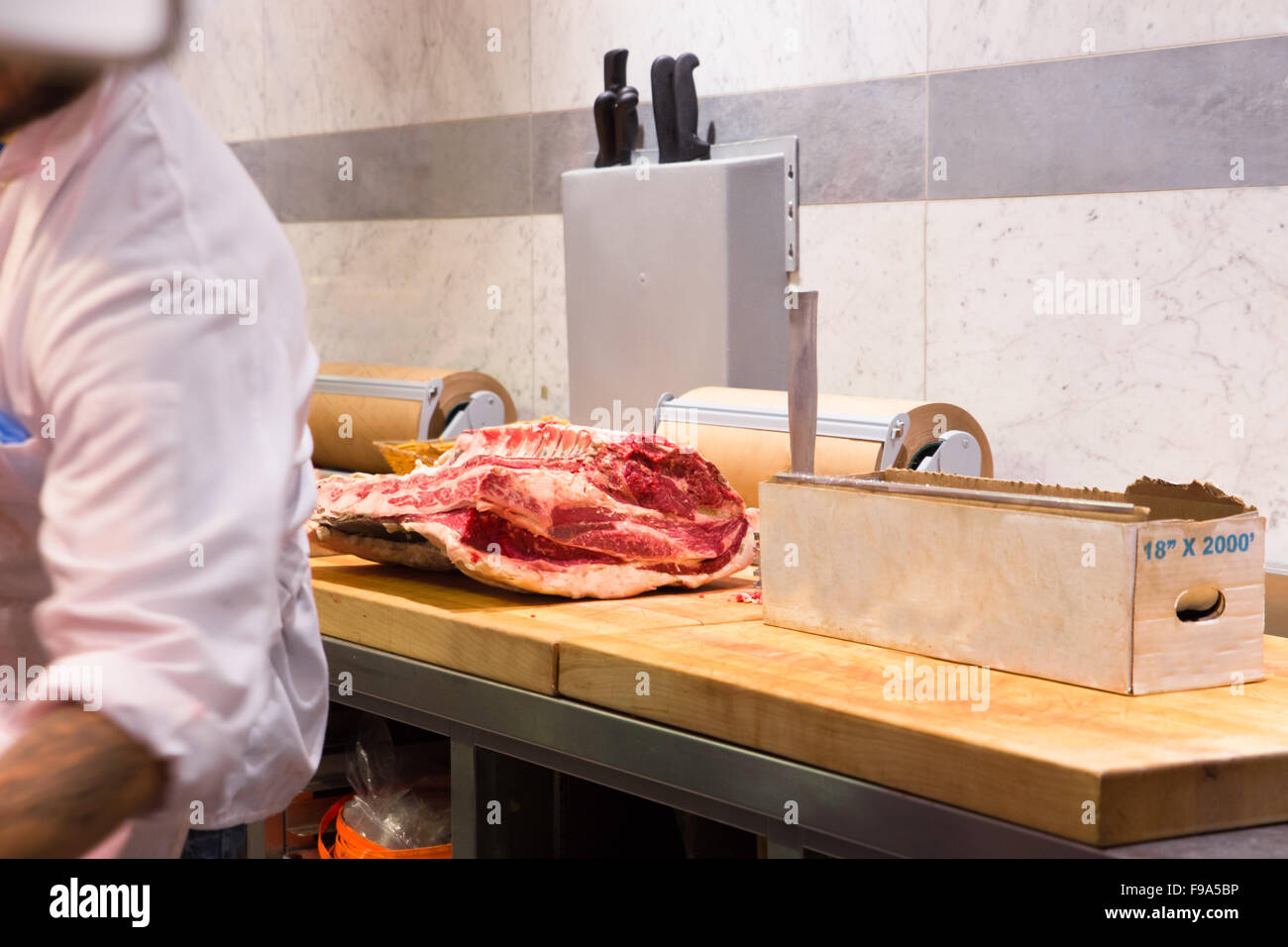 Vista della postazione di lavoro in macelleria con carne contatore e vista parziale del macellaio Foto Stock