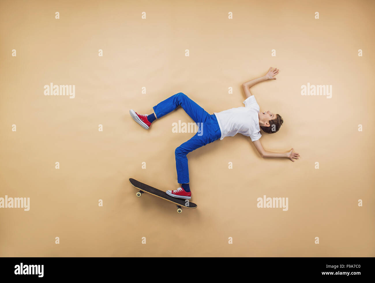 Ragazzo divertente è giocare con lo skateboard. Sdraiato sul pavimento. Foto Stock