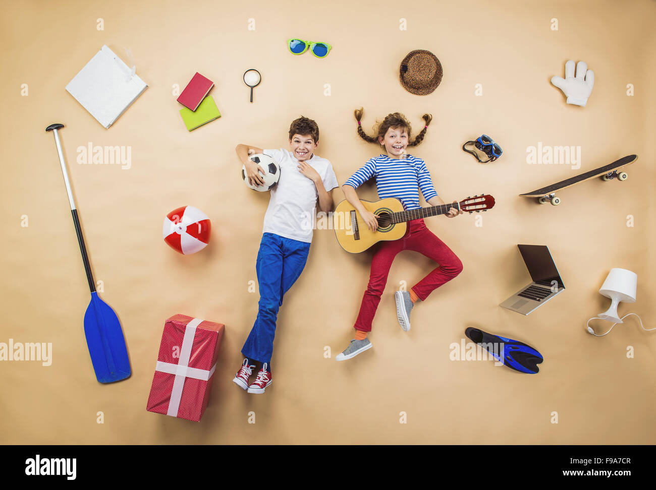 Divertenti sono i bambini a giocare insieme. Sdraiato sul pavimento con la chitarra e la sfera Foto Stock