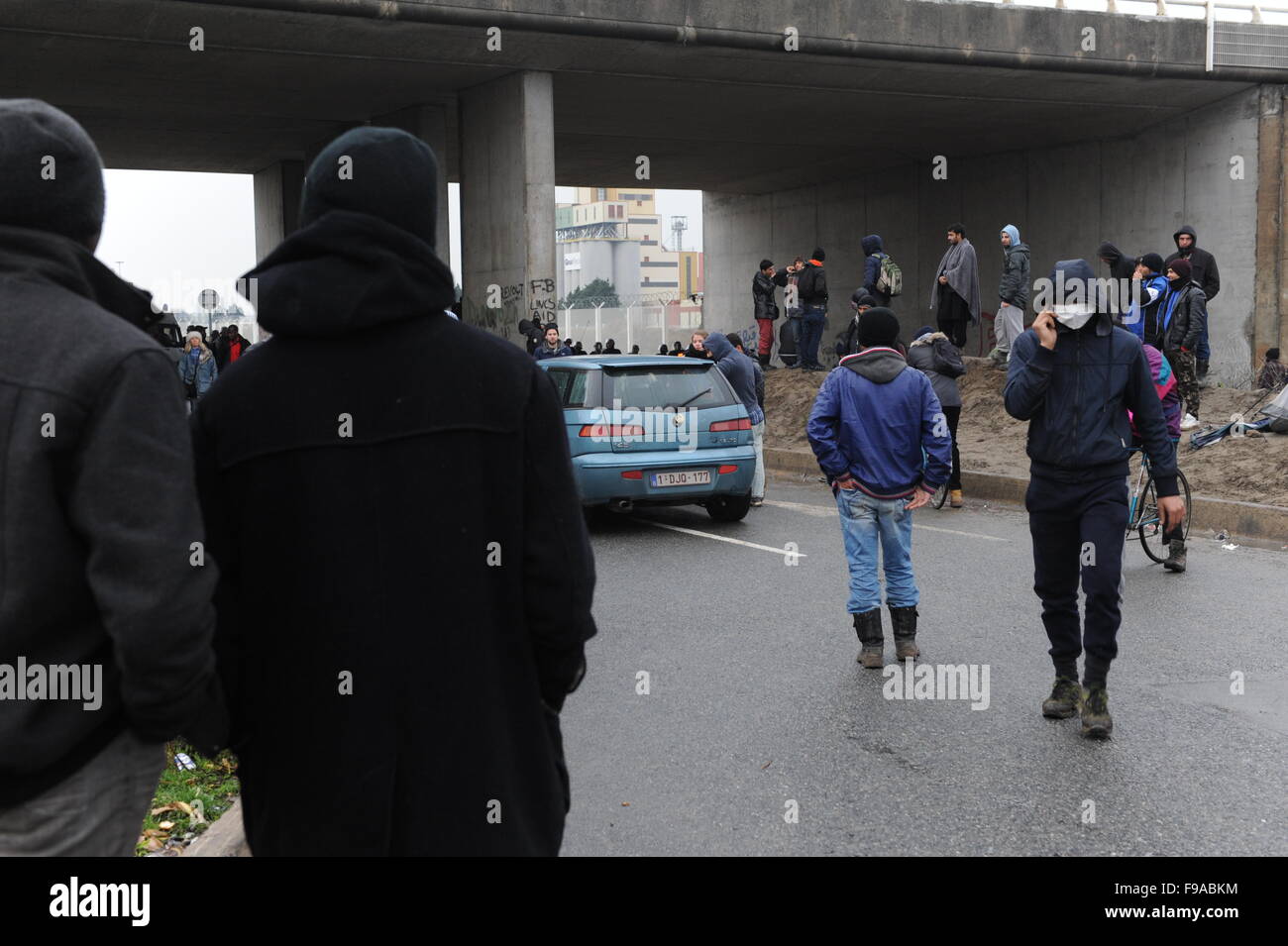 La giungla, Calais, Francia. Rifugiati e migranti bighellonare dall ingresso al camp dall'autostrada sorvegliato dalla polizia Foto Stock