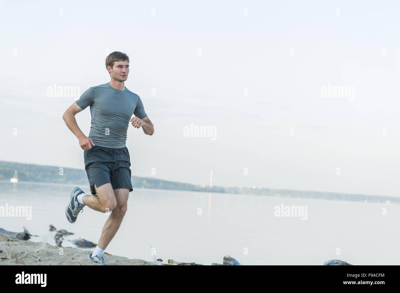 Runner atleta che corre in riva al mare a. L'uomo fitness jogging mattutino allenamento il concetto di benessere Foto Stock