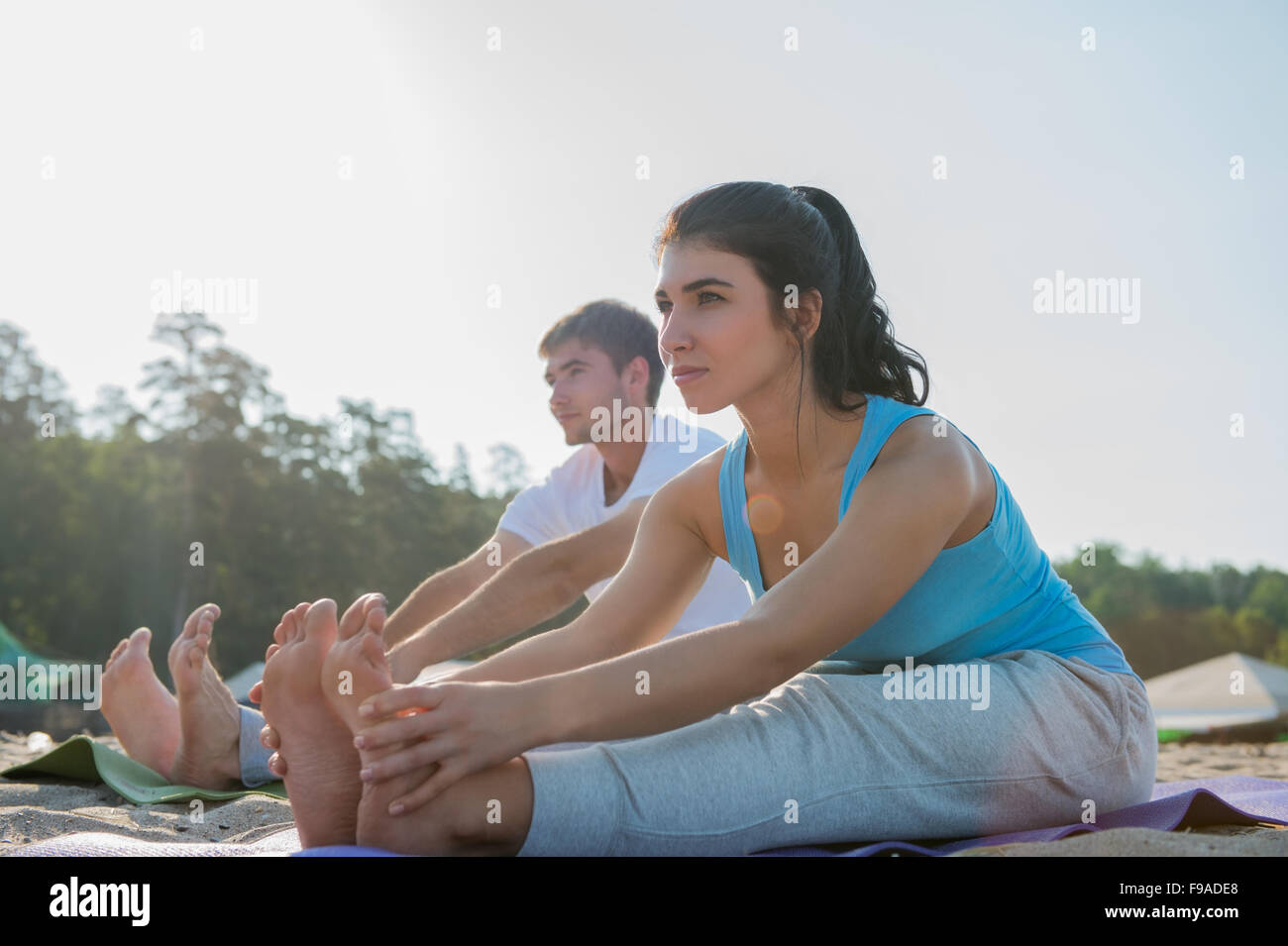 Coppia giovane facendo stretching esercizi yoga con il mare sullo sfondo Foto Stock
