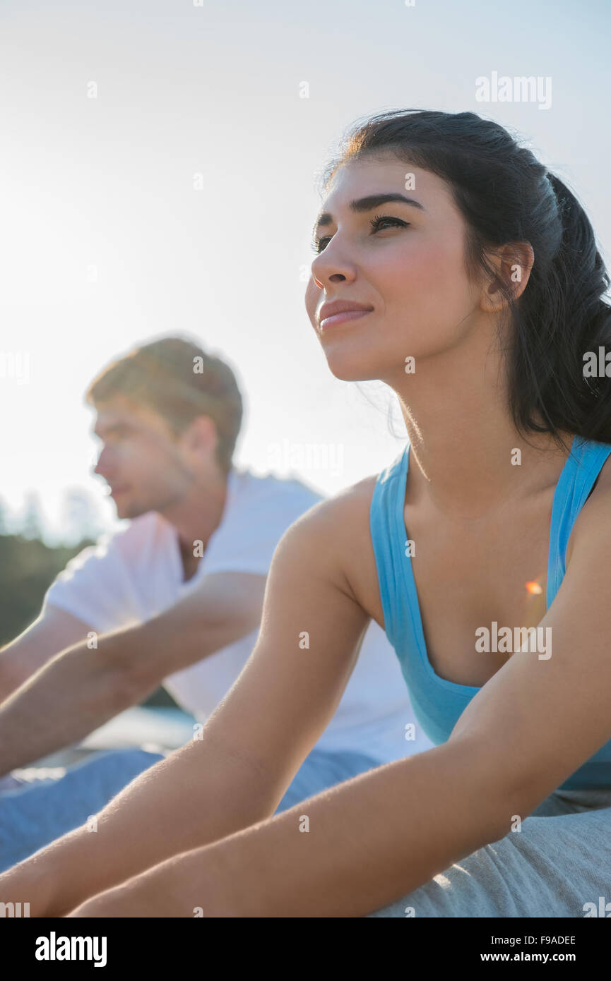 Coppia giovane facendo stretching esercizi yoga con il mare sullo sfondo Foto Stock