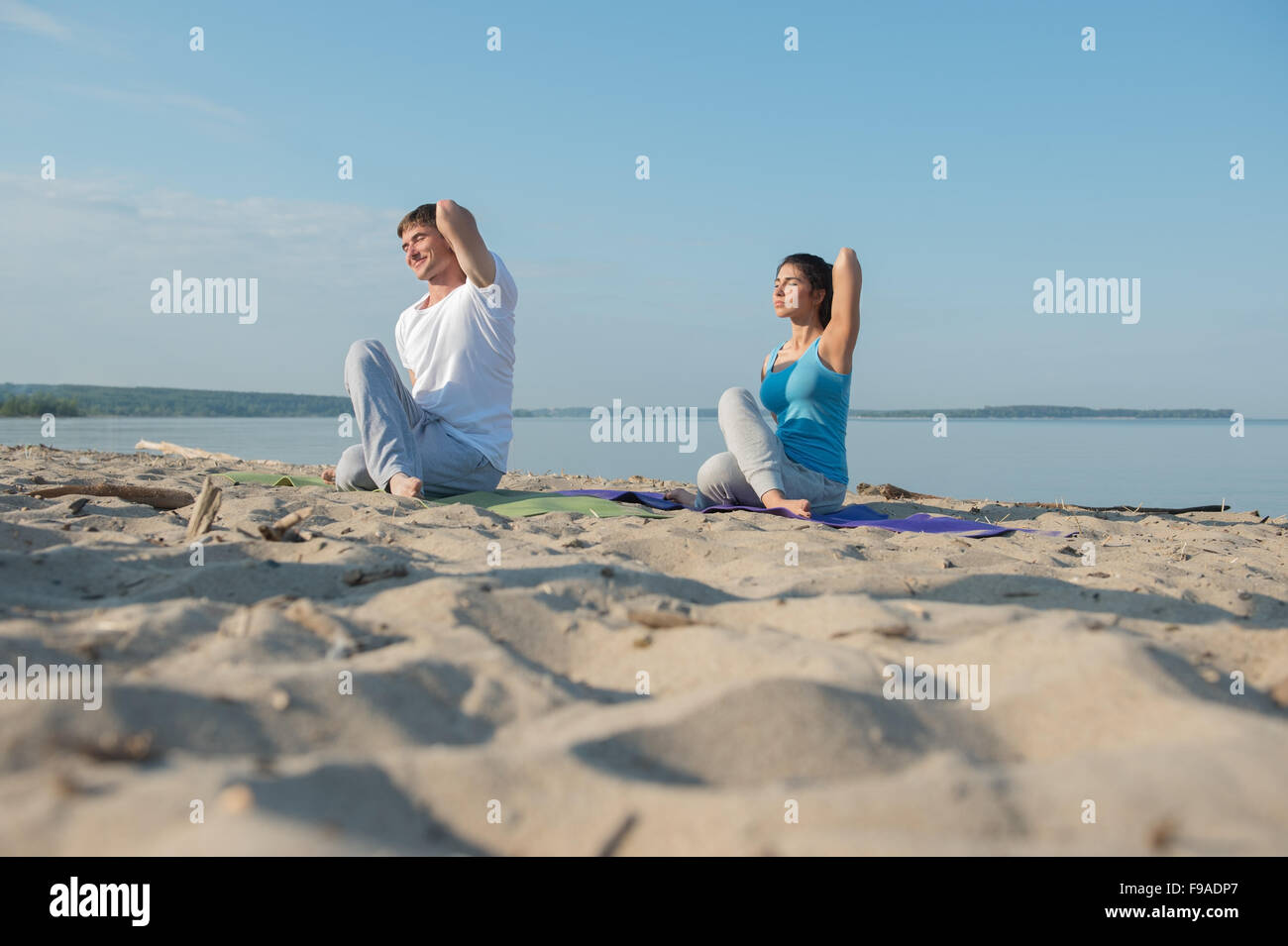 Coppia giovane facendo stretching esercizi yoga con il mare sullo sfondo Foto Stock