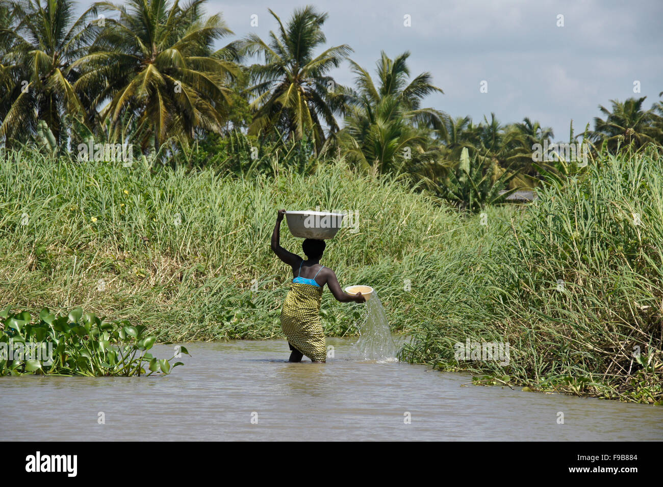 Fon donna recupero di acqua dal fiume Mono, villaggio di Heve-Grand Popo, Benin Foto Stock