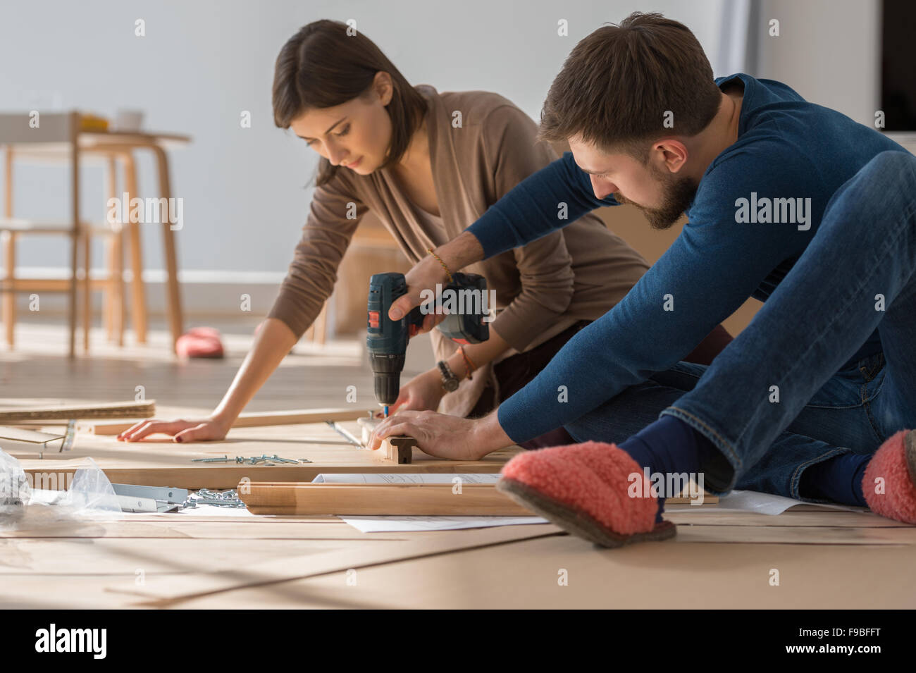 Felice coppia giovane mettendo insieme self montaggio dei mobili che si muovono nella loro nuova casa. Foto Stock