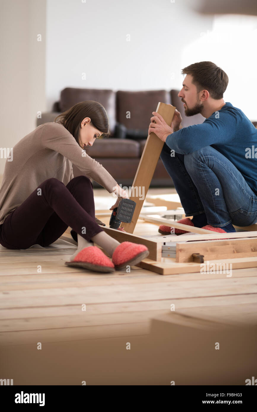 Felice coppia giovane mettendo insieme self montaggio dei mobili che si muovono nella loro nuova casa. Foto Stock