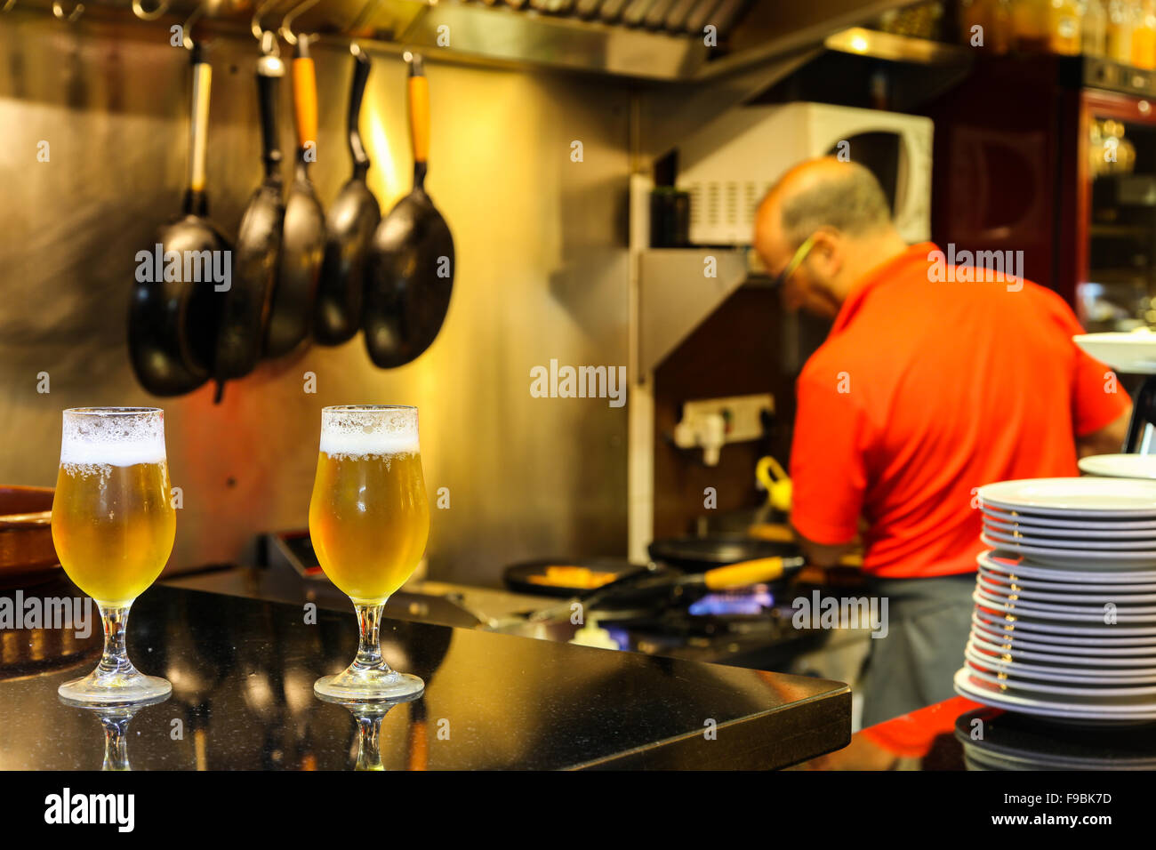 Due birre su un contatore in un tapas bar con lo chef cucinare in background Foto Stock
