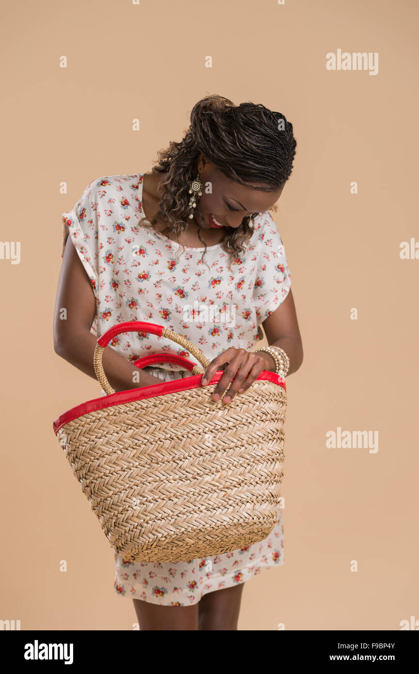 Ritratto di carino donna africana in posa - in piedi con la borsa di paglia Foto Stock