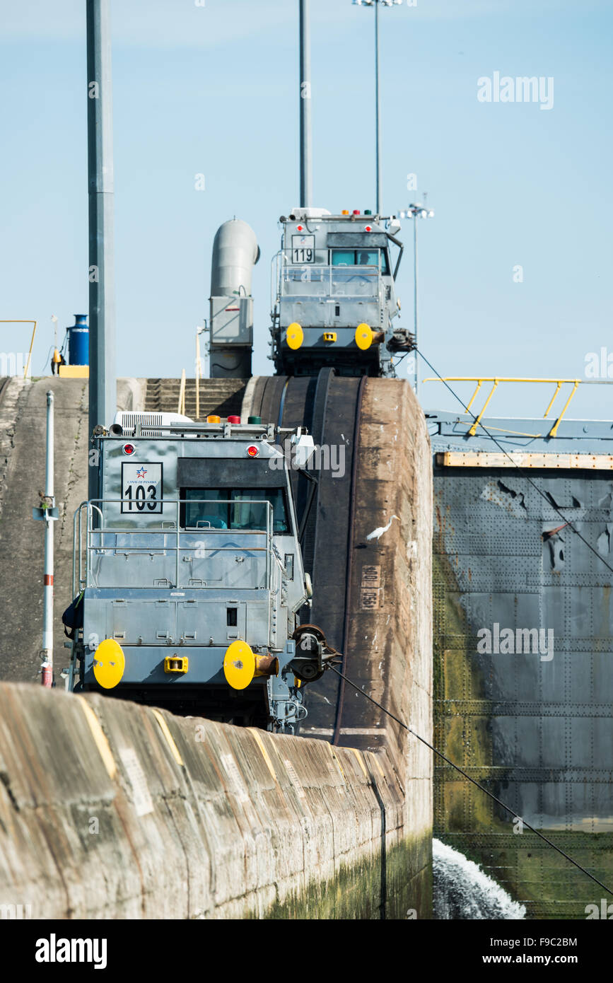 Serrande di Miraflores Canale di Panama Panama | CANALE DI PANAMA, Panama — Locomotive di traino, chiamate mule, si estendono sopra le pareti delle serrande di Miraflores, i loro cavi guidano una nave attraverso la camera sottostante sul lato Pacifico del Canale di Panama. Queste unità ferroviarie elettriche mantengono le navi centrate nelle camere larghe 110 piedi (33,53 m), un sistema immutato nel principio da quando le serrande sono state aperte nel 1914 come parte della via navigabile di circa 50 miglia (80 km). Foto Stock