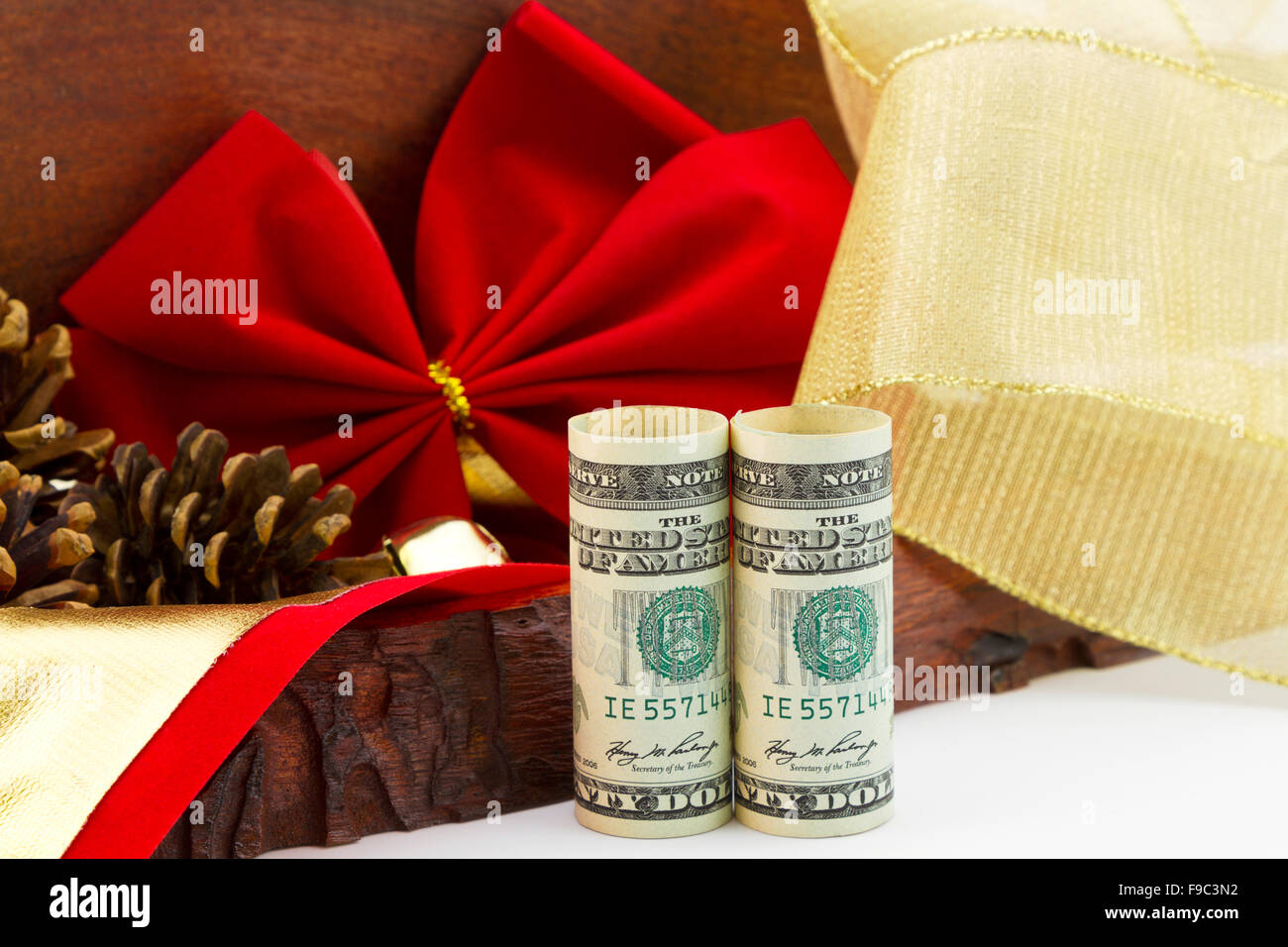 Dollari americani, un bonus di vacanza e di dono, stand by in legno rustico, scatola di velluto rosso a nastro, pigne e nastro color oro. Foto Stock