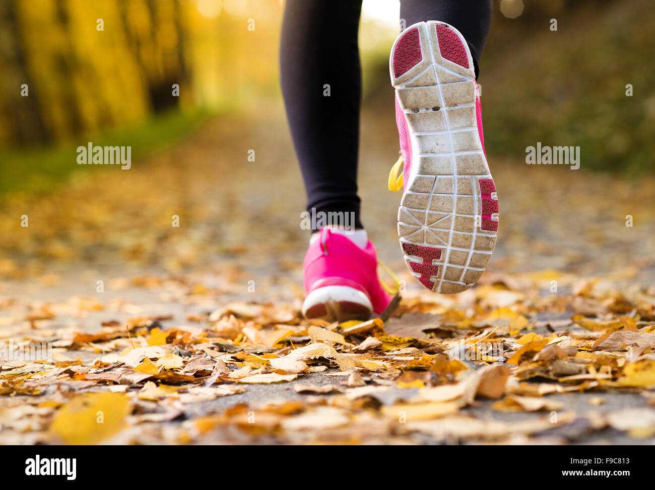 In prossimità dei piedi di un runner in esecuzione in foglie di autunno esercizio Foto Stock