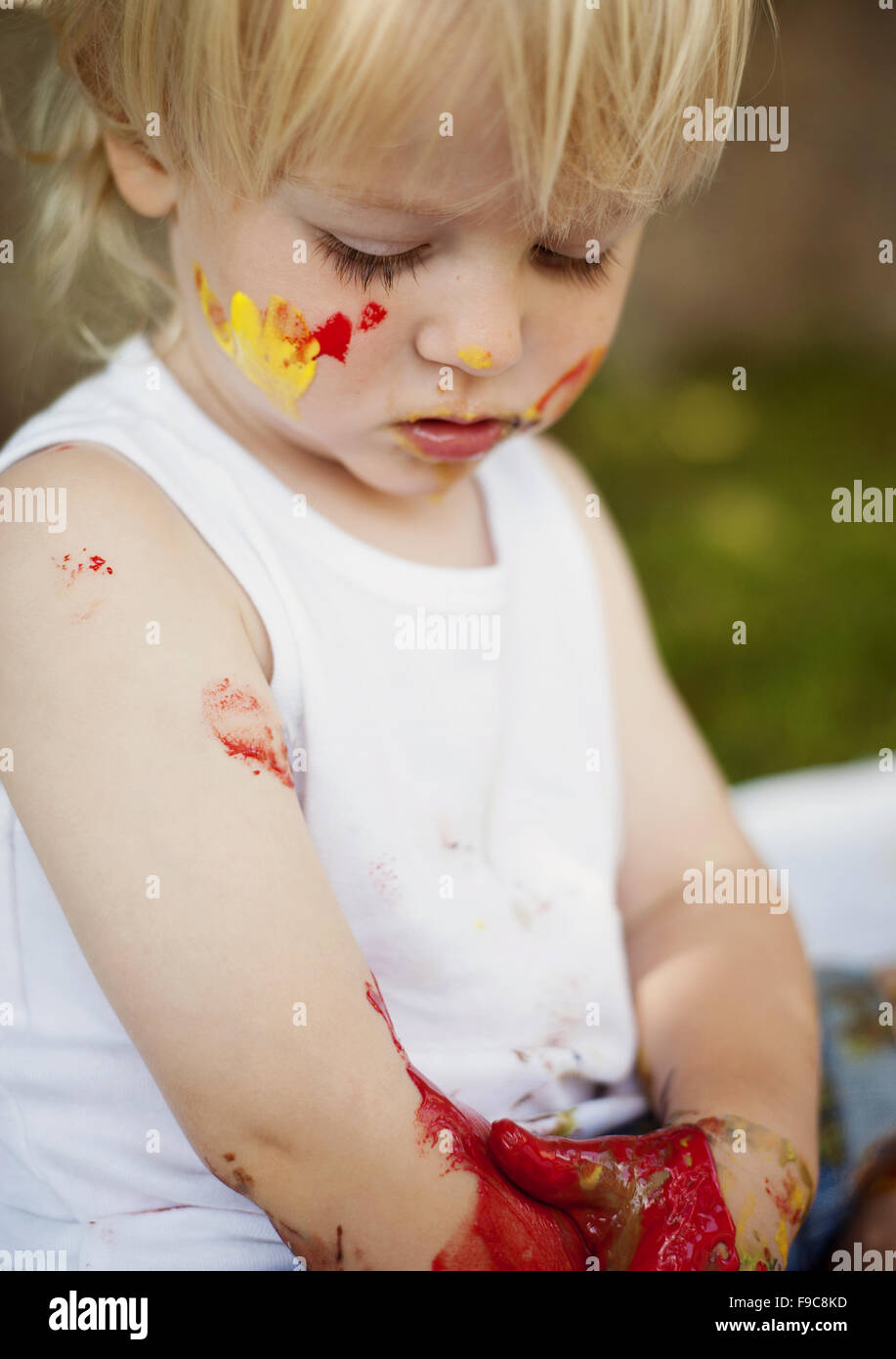 Carino bambino dipinto con colori vivaci in giardino Foto Stock