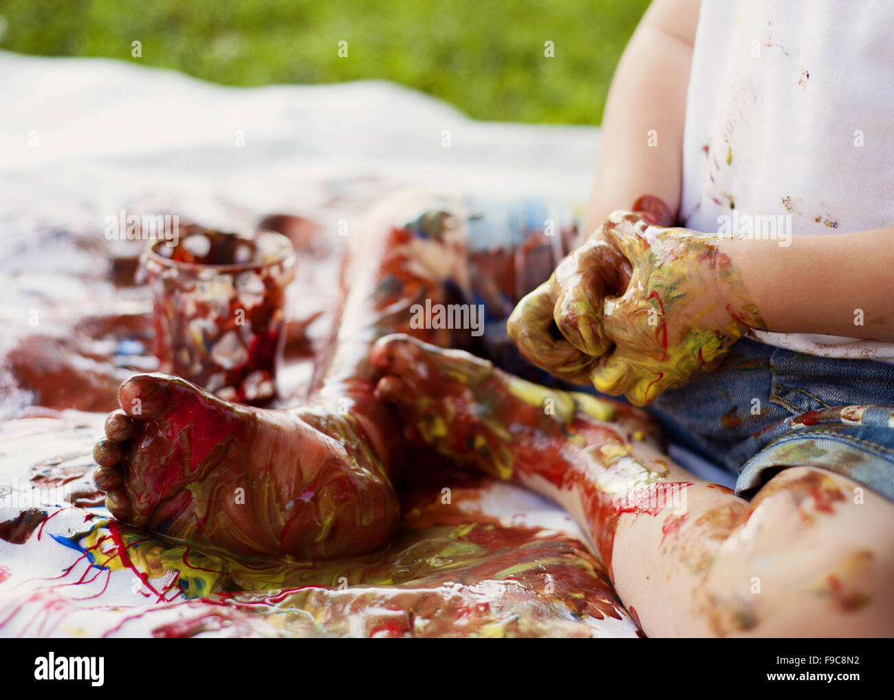 Carino bambino dipinto con colori vivaci in giardino Foto Stock