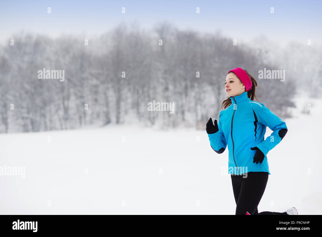 Atleta donna è in esecuzione durante gli allenamenti invernali al di fuori nella neve fredda meteo. Foto Stock