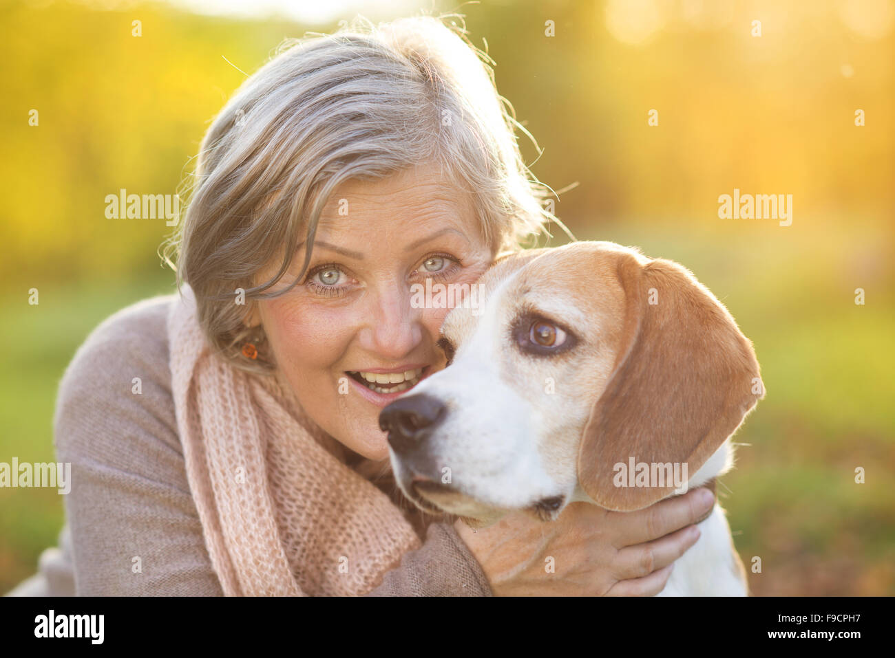 Senior donna avvolge il suo cane beagle in campagna Foto Stock