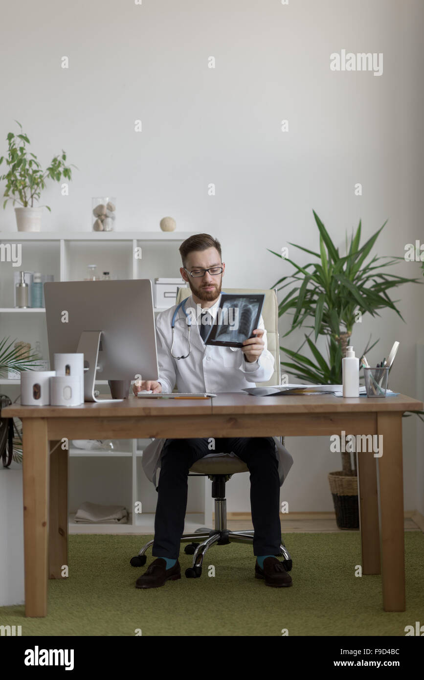 Riflessivo medico tenendo il petto e polmoni xray in ufficio medico Foto Stock