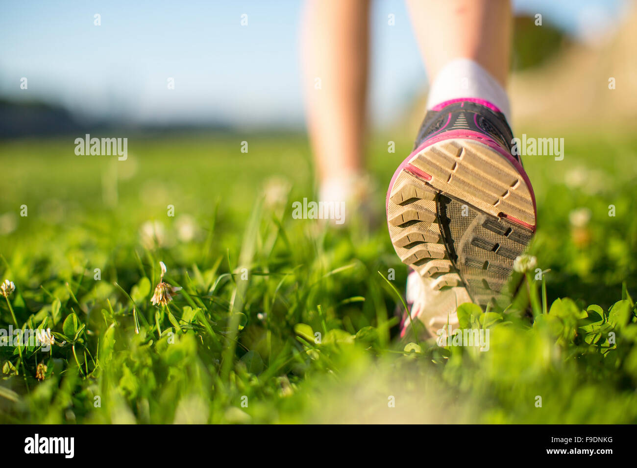 Closeup runner piedi correndo all'aperto sull'erba verde. Foto Stock