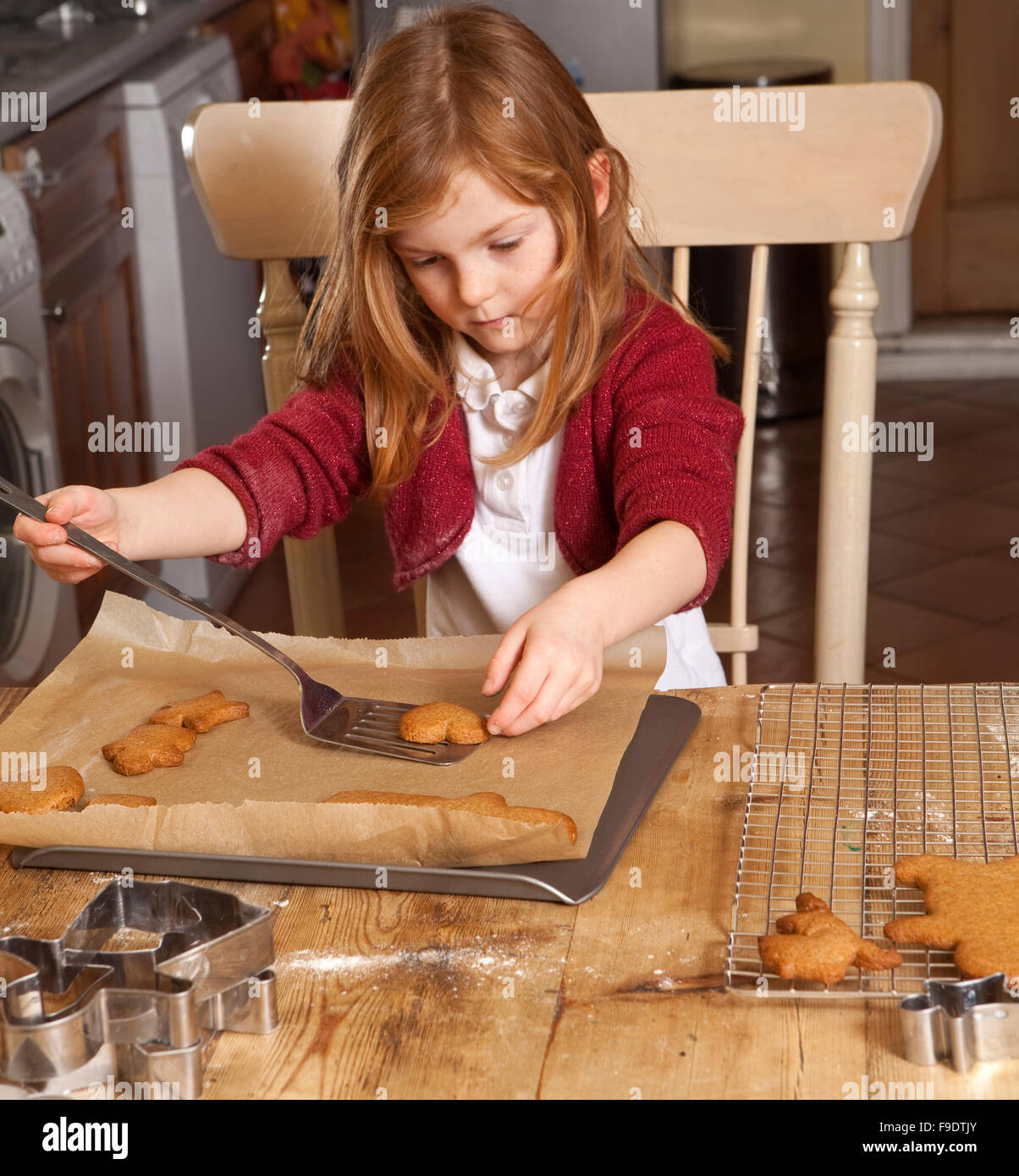 Direttamente dal forno. Il pan di zenzero è stata cotta e la giovane ragazza è attentamente prendendo il pane caldo dal vassoio. Foto Stock