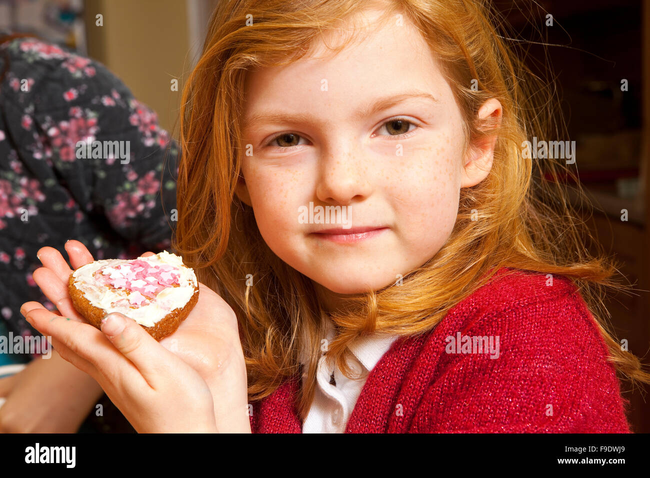 Guardate cosa ho fatto. Una giovane bambina di cinque anni tiene i suoi Gingerbread creazione decorata con glassa e rosa e bianco candy stelle Foto Stock