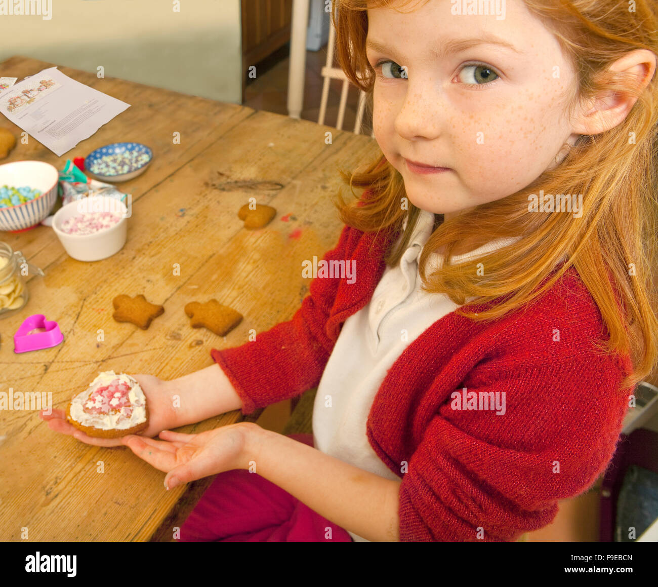 Guardate cosa ho fatto. Una giovane bambina di cinque anni tiene i suoi Gingerbread creazione decorata con glassa e rosa e bianco candy stelle Foto Stock