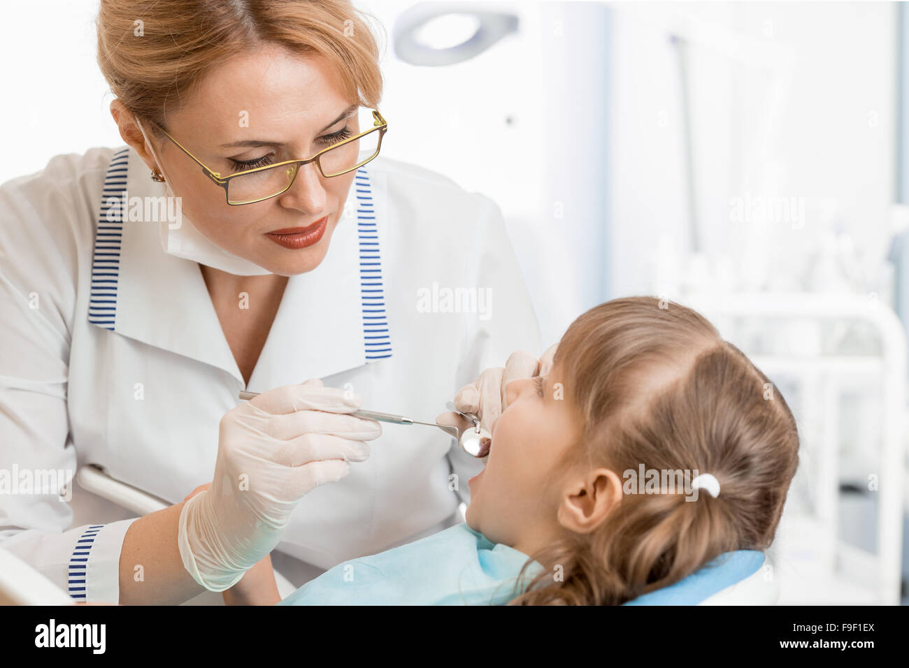 Dentista donna esaminando kid paziente in ufficio Foto Stock