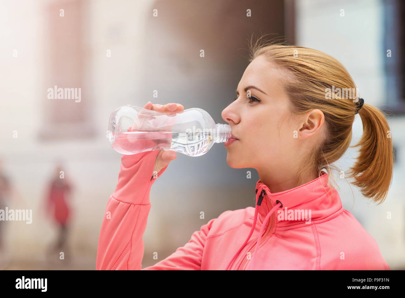 Bella giovane donna in esecuzione nella città di concorrenza acqua potabile al punto refresment Foto Stock