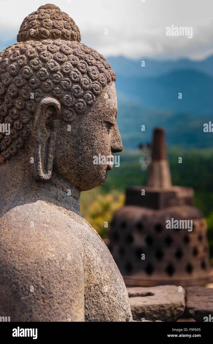 Meditando Budda seduto sculputre veduta laterale in pietra a Borobudur Foto Stock