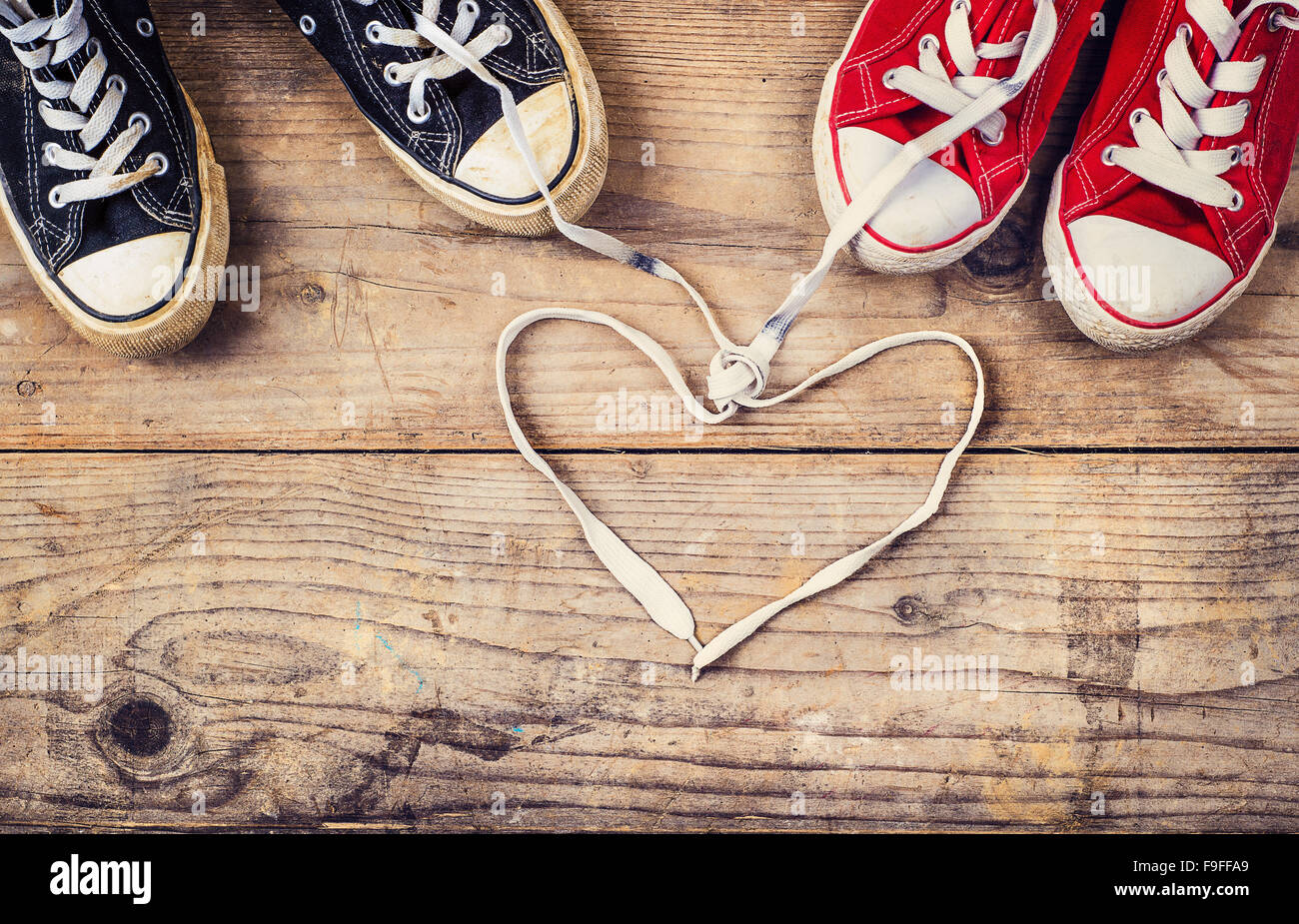 Originale il giorno di San Valentino il concetto di amore con il rosso e il nero sneakers. Studio shot su un pavimento di legno dello sfondo. Foto Stock