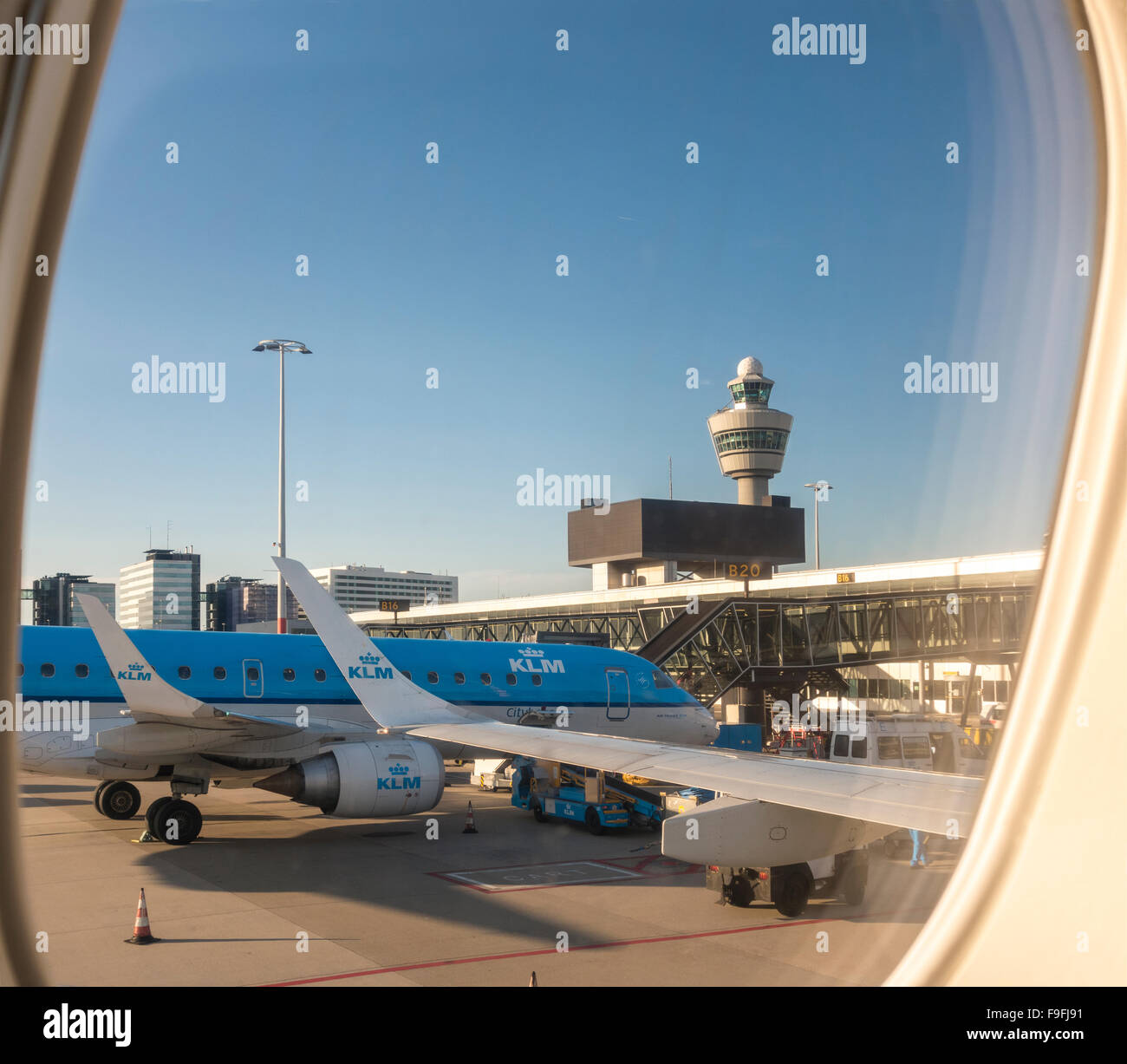 L'aeroporto Schiphol di Amsterdam con KLM Cityhopper PH-EZO Embraer E-190 piano in corrispondenza della gate e la torre di controllo. Vista da una finestra sede Foto Stock