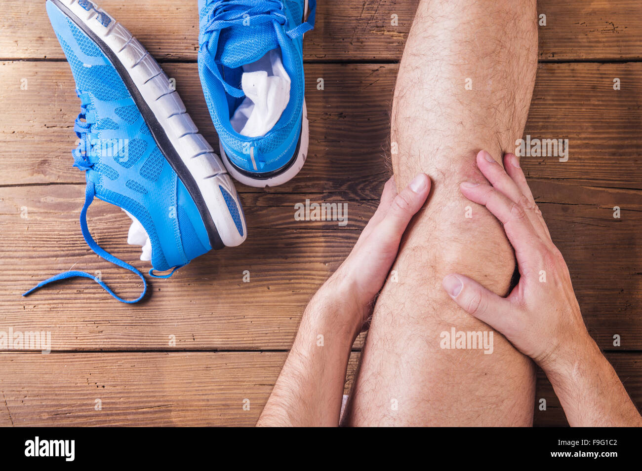 Irriconoscibile feriti runner seduto su un pavimento di legno sfondo Foto Stock
