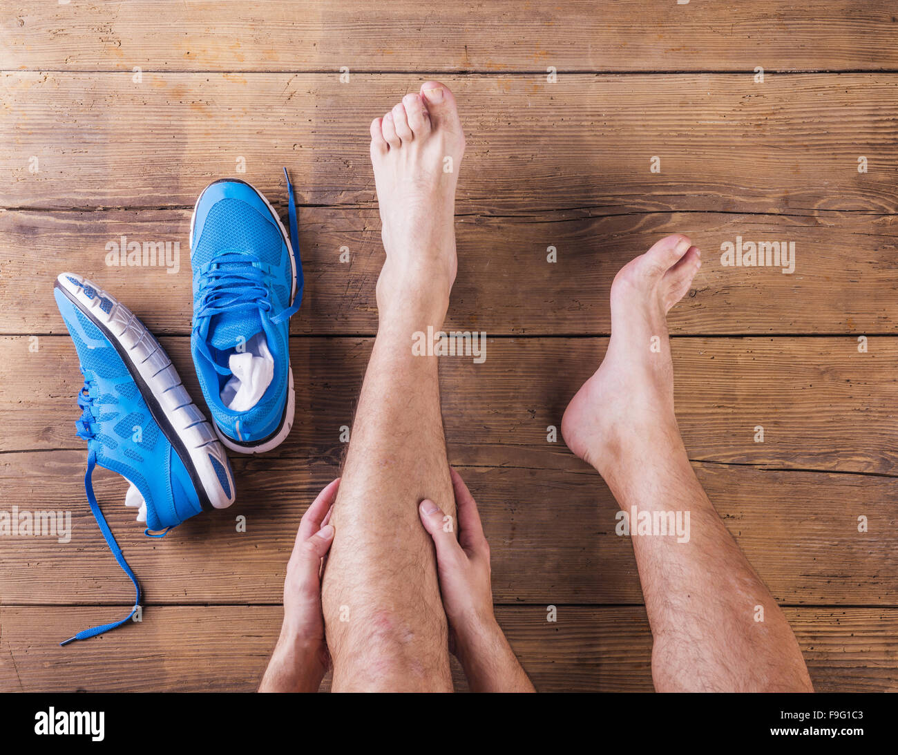 Irriconoscibile feriti runner seduto su un pavimento di legno sfondo Foto Stock