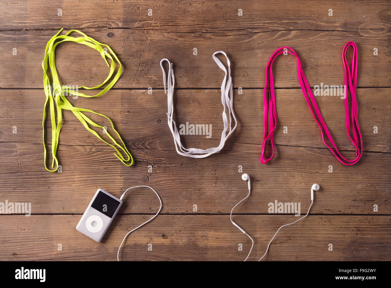 Lacci delle scarpe eseguire il segno e il lettore mp3 su un pavimento di legno sfondo Foto Stock