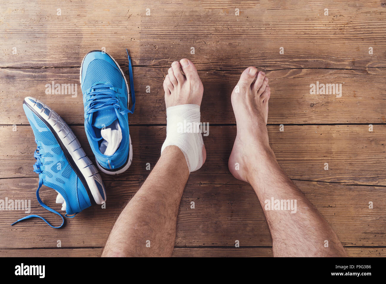 Irriconoscibile feriti runner seduto su un pavimento di legno sfondo Foto Stock
