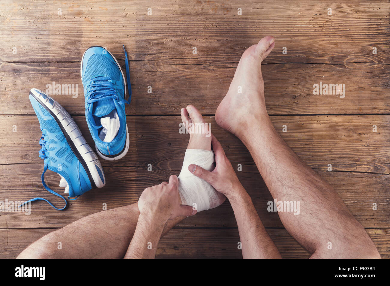 Irriconoscibile feriti runner seduto su un pavimento di legno sfondo Foto Stock