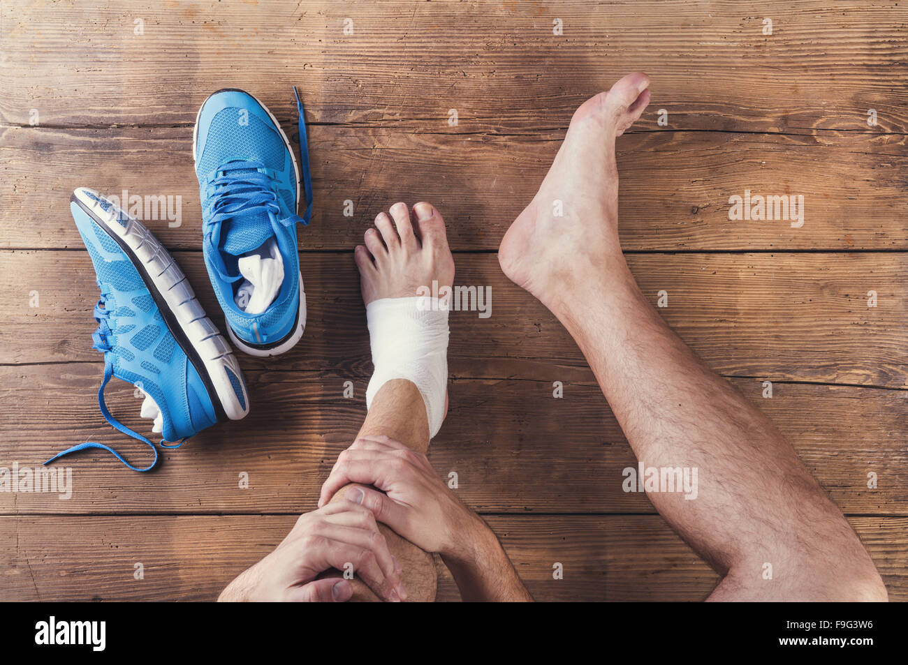 Irriconoscibile feriti runner seduto su un pavimento di legno sfondo Foto Stock