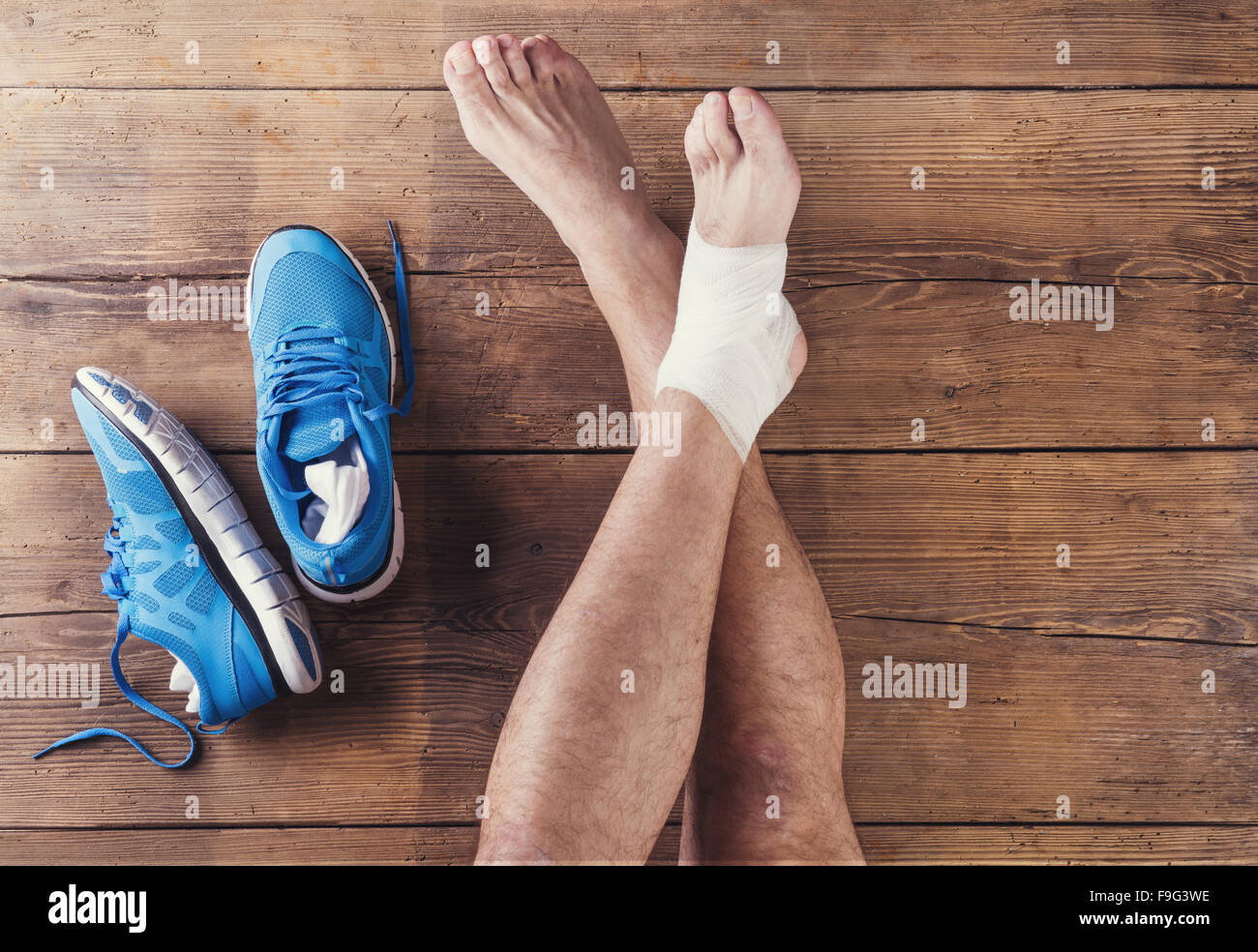 Irriconoscibile feriti runner seduto su un pavimento di legno sfondo Foto Stock