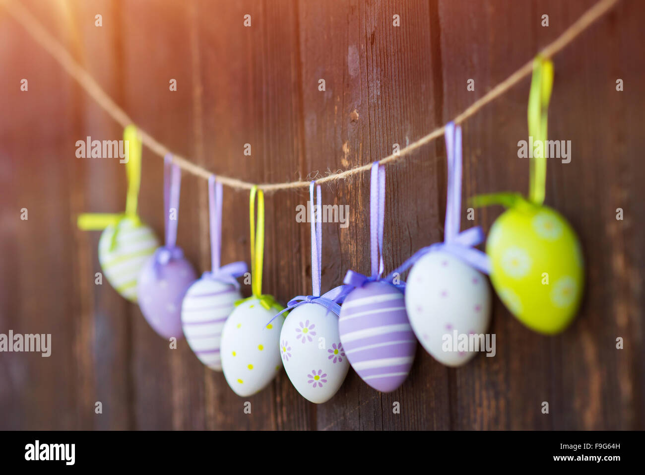 Colorate le uova di pasqua appeso su un lo spago alla parete in legno sfondo. Foto Stock