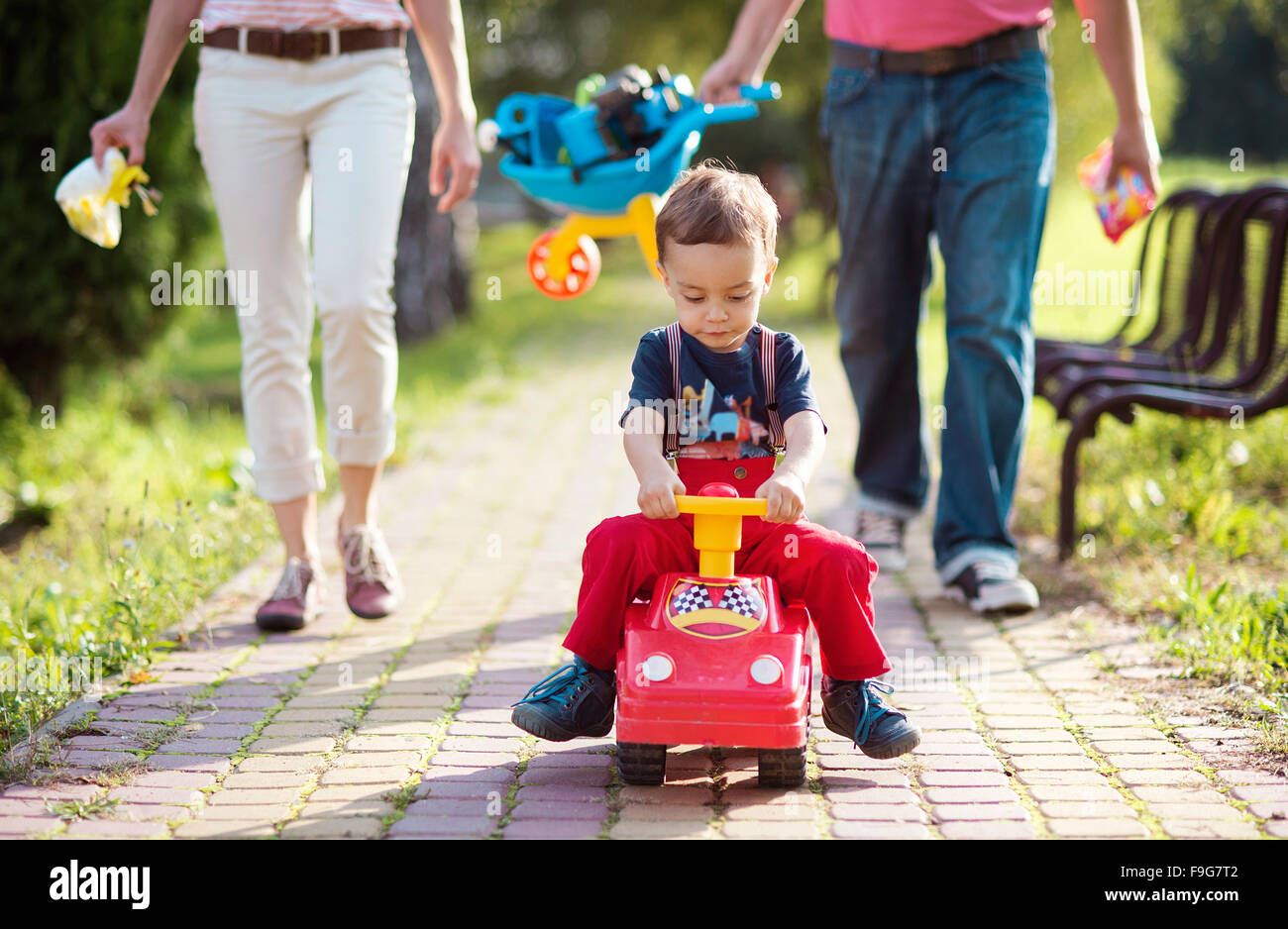 Felice famiglia giovane a piedi attraverso il parco durante un giorno di estate Foto Stock