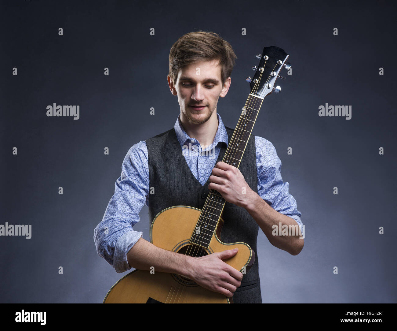 Bel giovane chitarrista. Studio shot su sfondo nero. Foto Stock