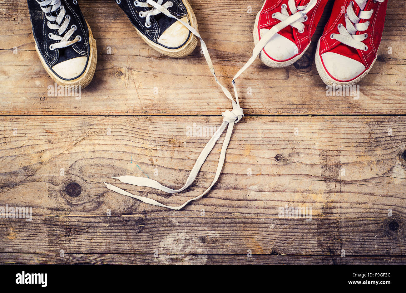 Originale il giorno di San Valentino il concetto di amore con il rosso e il nero sneakers. Studio shot su un pavimento di legno dello sfondo. Foto Stock