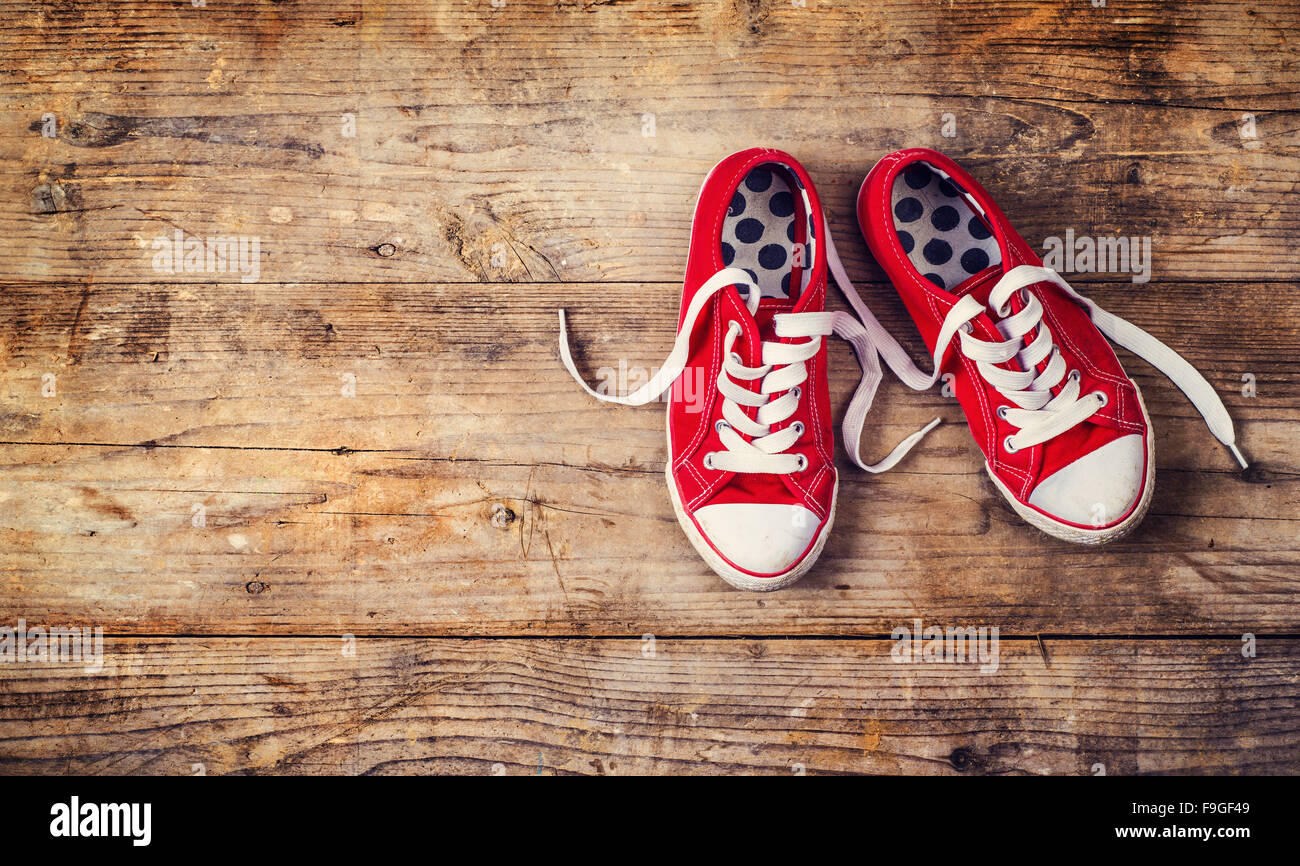 Coppia di red sneakers su un pavimento. Studio shot su uno sfondo di legno. Foto Stock