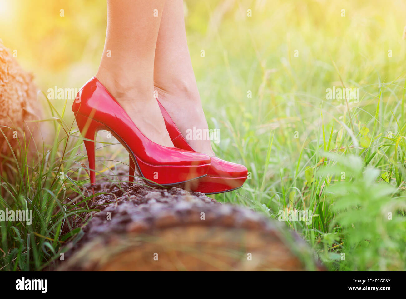 Irriconoscibile giovane donna di indossare tacchi rosso in piedi su un log Foto Stock