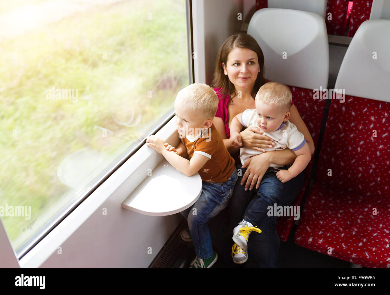 Madre con figli in grembo che viaggiano in treno. Foto Stock