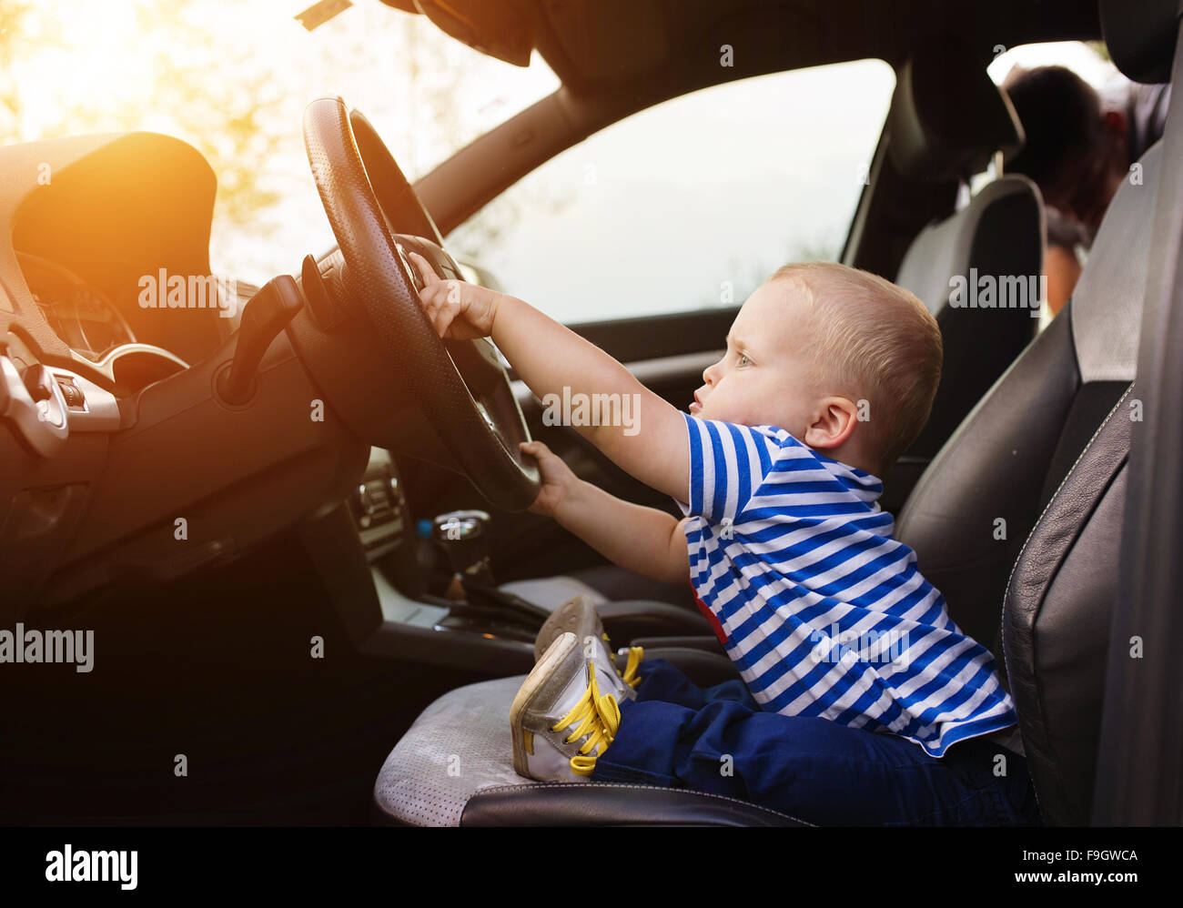 Little Boy giocando con un volante in un auto Foto Stock