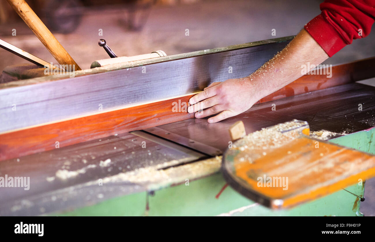 Le mani del falegname lavora con legno elettrico ruspa nel suo laboratorio Foto Stock